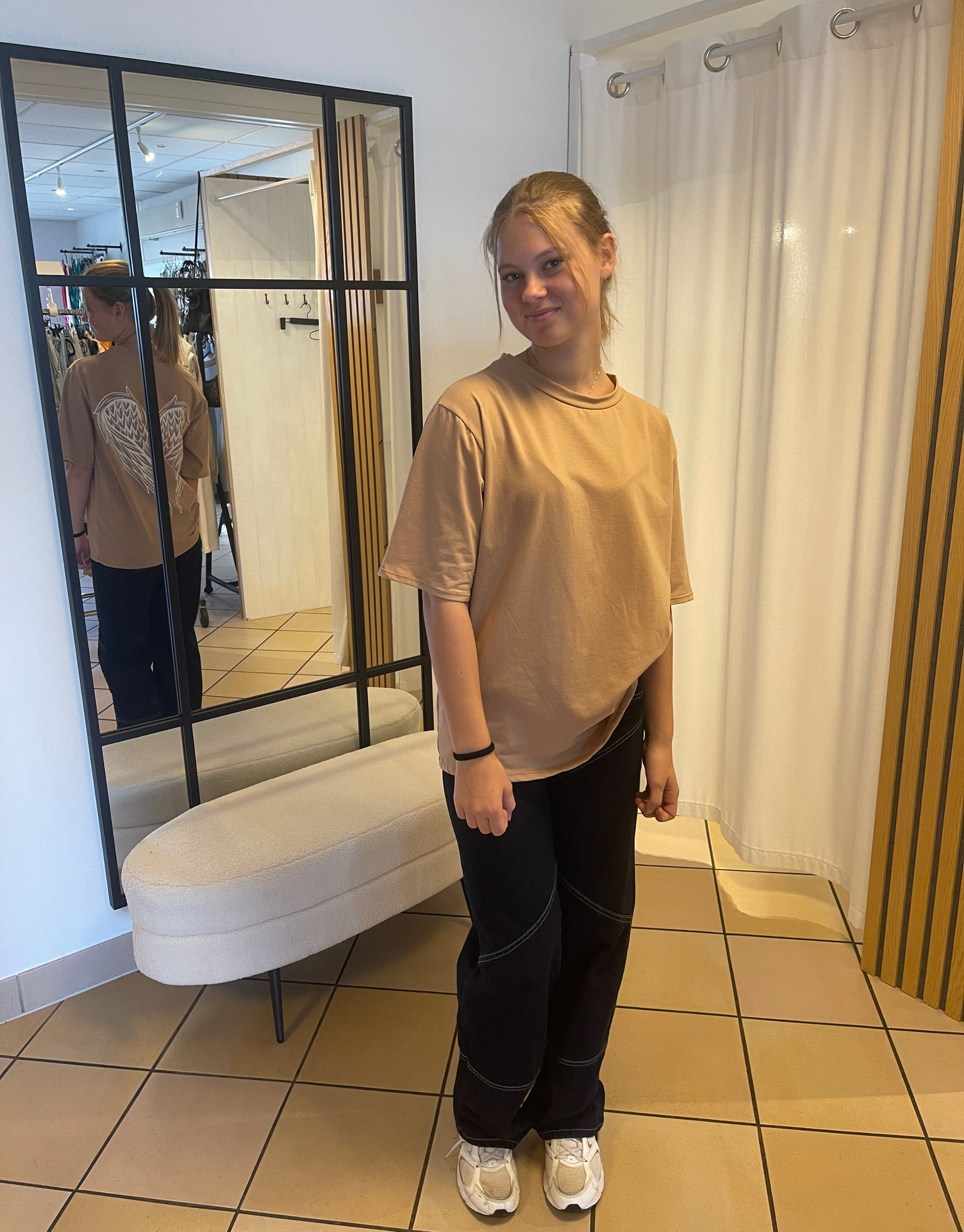 Oversized t-shirt i en flot mørk beige med vinge design på ryggen.