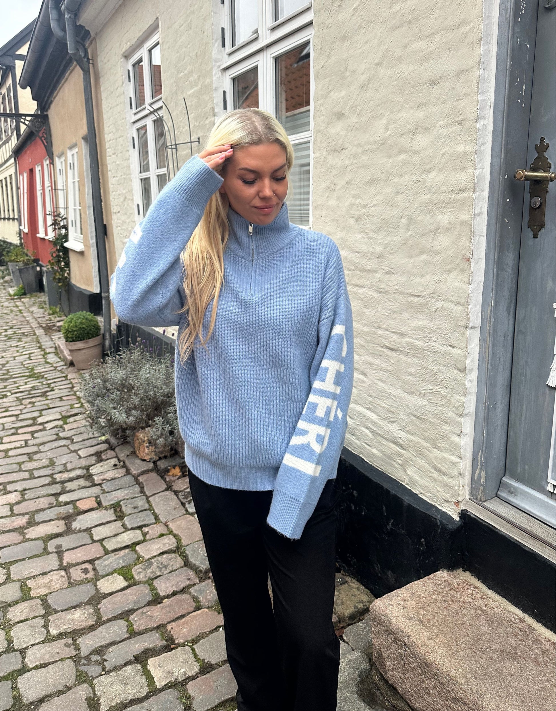 Lækker højhalset strik med Mon Cheri tekst på ærmerne.